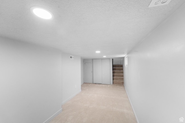 hall with light carpet, stairway, a textured ceiling, and baseboards