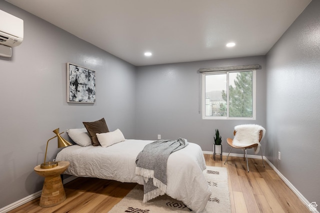 bedroom featuring a wall mounted air conditioner, light wood finished floors, recessed lighting, and baseboards