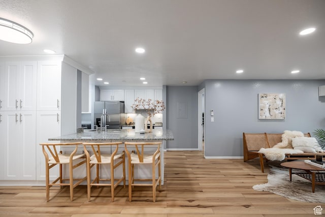 dining space with recessed lighting, light wood-style flooring, and baseboards
