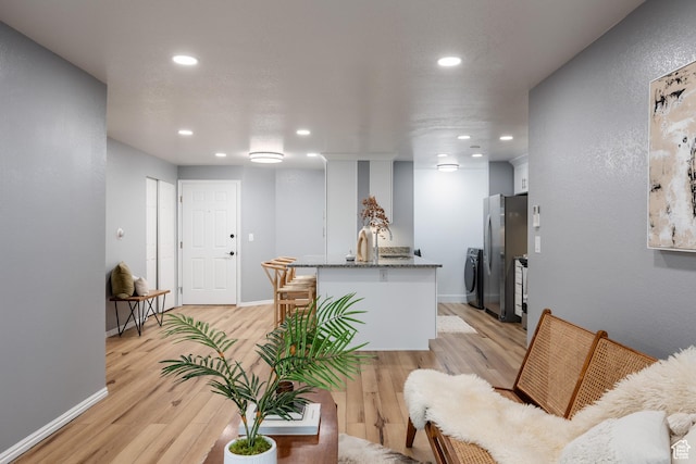 living room with washer / dryer, light wood finished floors, recessed lighting, and baseboards