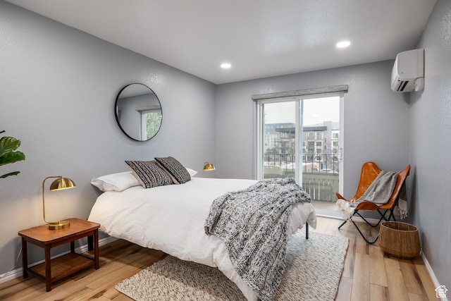 bedroom featuring an AC wall unit, light wood finished floors, access to exterior, baseboards, and recessed lighting