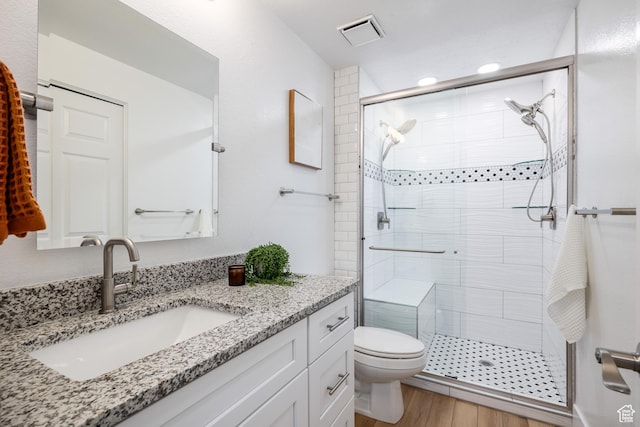bathroom with a stall shower, toilet, vanity, and wood finished floors