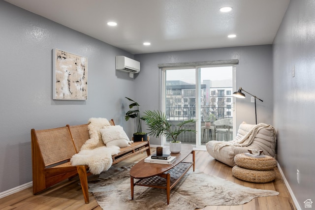 sitting room featuring a wall mounted AC, light wood-style floors, recessed lighting, and baseboards