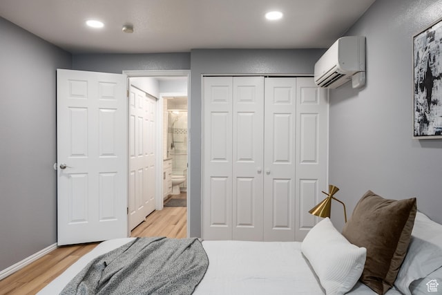 bedroom with a wall mounted AC, light wood-style floors, recessed lighting, a closet, and baseboards