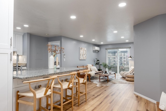 dining room featuring recessed lighting, light wood-type flooring, baseboards, and an AC wall unit