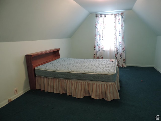 bedroom featuring lofted ceiling, dark carpet, and baseboards