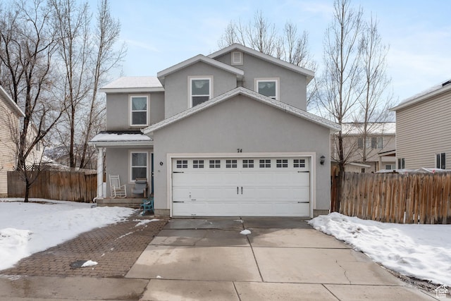 traditional-style house featuring stucco siding, driveway, and fence