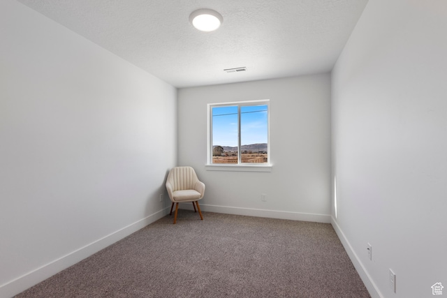unfurnished room with carpet floors, visible vents, baseboards, and a textured ceiling