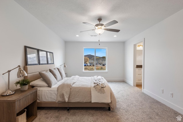 carpeted bedroom with visible vents, a textured ceiling, baseboards, and ensuite bathroom