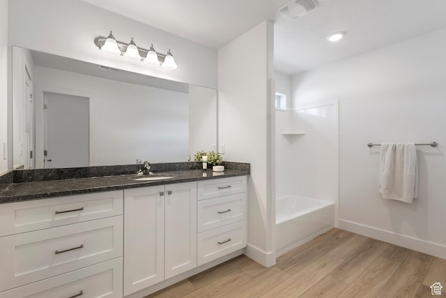 bathroom with tub / shower combination, vanity, baseboards, and wood finished floors