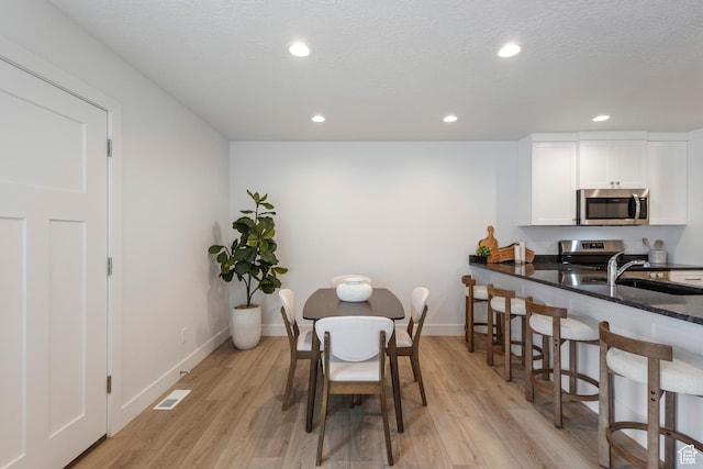 dining space with baseboards, light wood-style flooring, visible vents, and recessed lighting