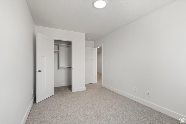 unfurnished bedroom featuring a textured ceiling, carpet floors, a closet, and baseboards