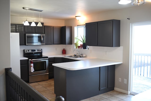 kitchen featuring stainless steel appliances, a peninsula, a sink, and light countertops
