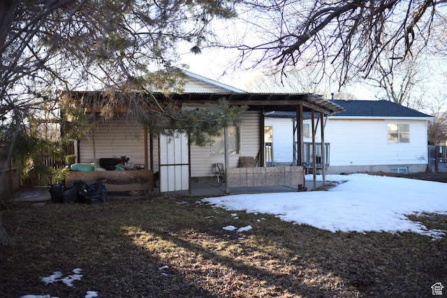 snow covered rear of property with covered porch