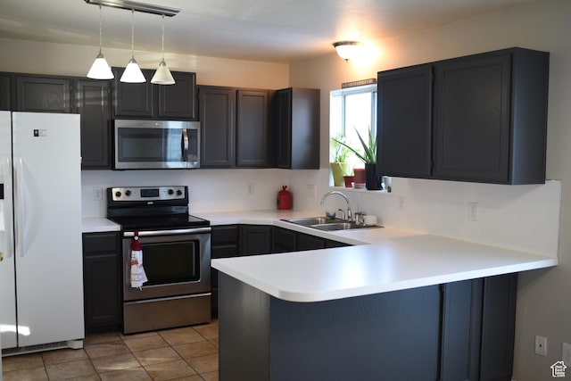 kitchen featuring light countertops, hanging light fixtures, appliances with stainless steel finishes, a sink, and a peninsula