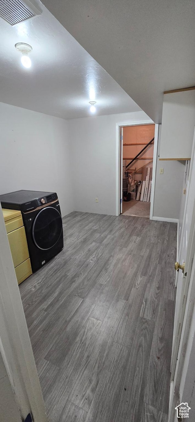 below grade area with washing machine and dryer, visible vents, and wood finished floors