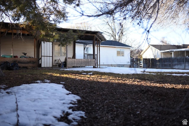 snow covered rear of property with fence and a porch