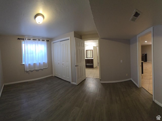 interior space featuring a closet, dark wood-style flooring, visible vents, and baseboards