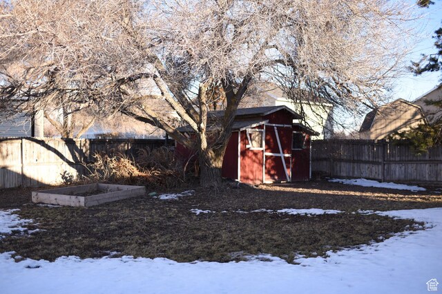 snowy yard with an outbuilding, a shed, and fence private yard