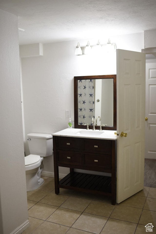 bathroom featuring baseboards, vanity, toilet, and tile patterned floors