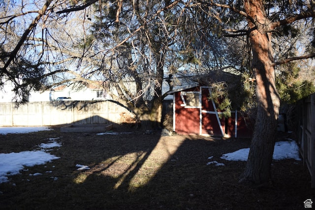 view of yard featuring fence, a storage unit, and an outbuilding