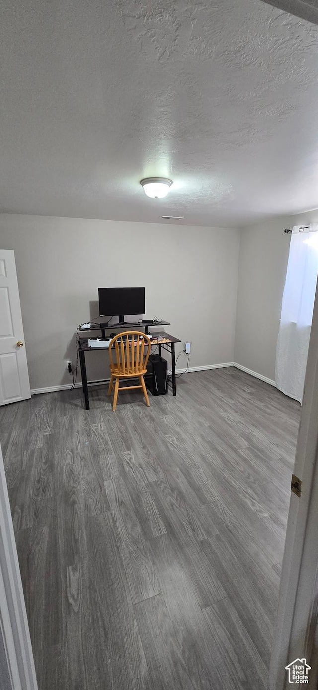 home office with a textured ceiling, wood finished floors, and baseboards