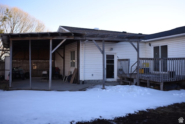 snow covered rear of property featuring a patio and a wooden deck