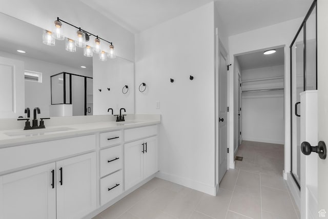full bathroom with double vanity, a stall shower, a walk in closet, and a sink