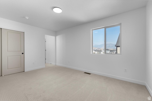 empty room featuring light carpet, baseboards, and visible vents
