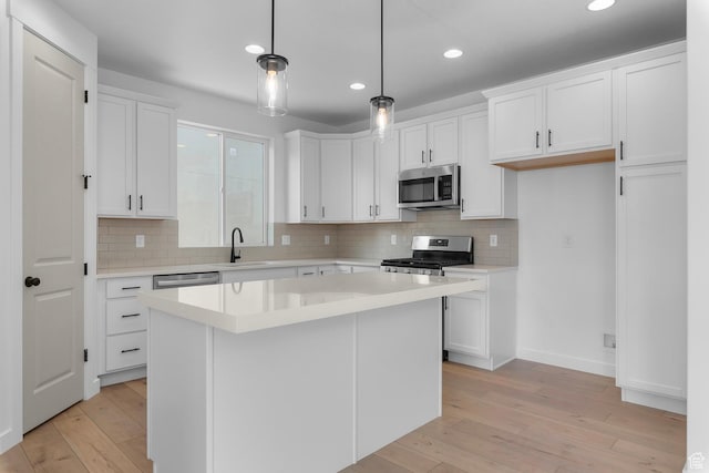 kitchen featuring a sink, white cabinetry, light wood-style floors, light countertops, and appliances with stainless steel finishes