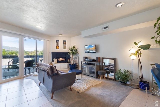 5354 S Baldwin Park, Murray, UT 84123 - living room featuring a warm lit fireplace, visible vents, a textured ceiling, and tile patterned floors