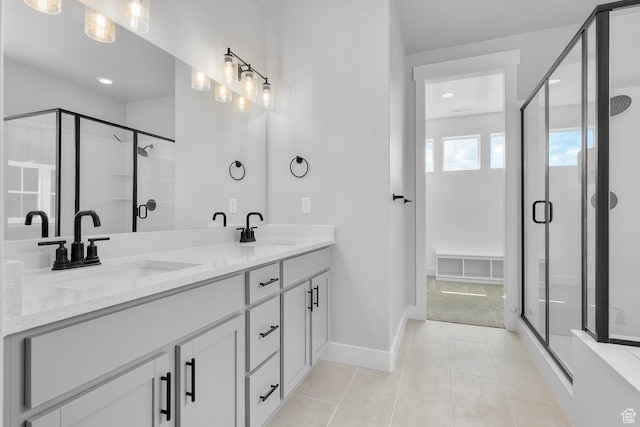 bathroom with double vanity, a shower stall, a sink, and tile patterned floors