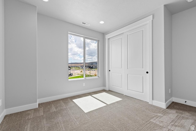 unfurnished bedroom featuring carpet floors, a closet, visible vents, and baseboards