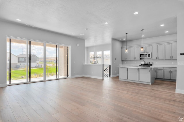 kitchen with a sink, stainless steel appliances, light wood finished floors, and light countertops