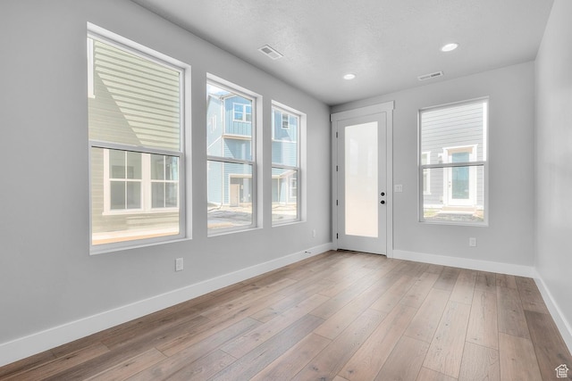 interior space with a textured ceiling, recessed lighting, visible vents, baseboards, and wood-type flooring