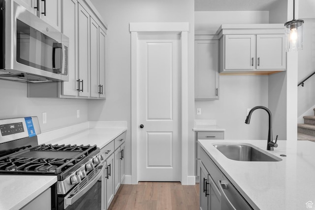 kitchen featuring light countertops, appliances with stainless steel finishes, a sink, and light wood-style flooring