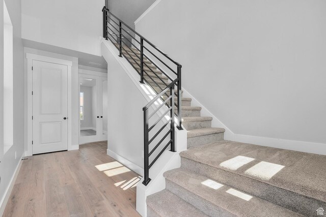 stairway with a towering ceiling, baseboards, and wood finished floors