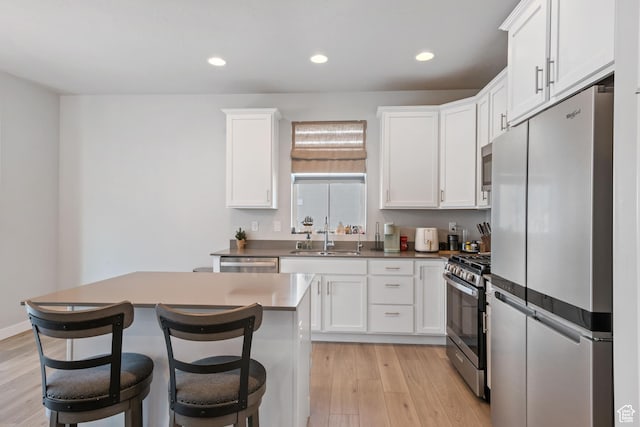 5715 Brambling Way E, Stansbury Park, UT 84074 - kitchen featuring white cabinets, light wood-type flooring, stainless steel appliances, and a sink