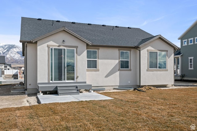 5715 Brambling Way E, Stansbury Park, UT 84074 - rear view of house with entry steps, roof with shingles, stucco siding, and a lawn