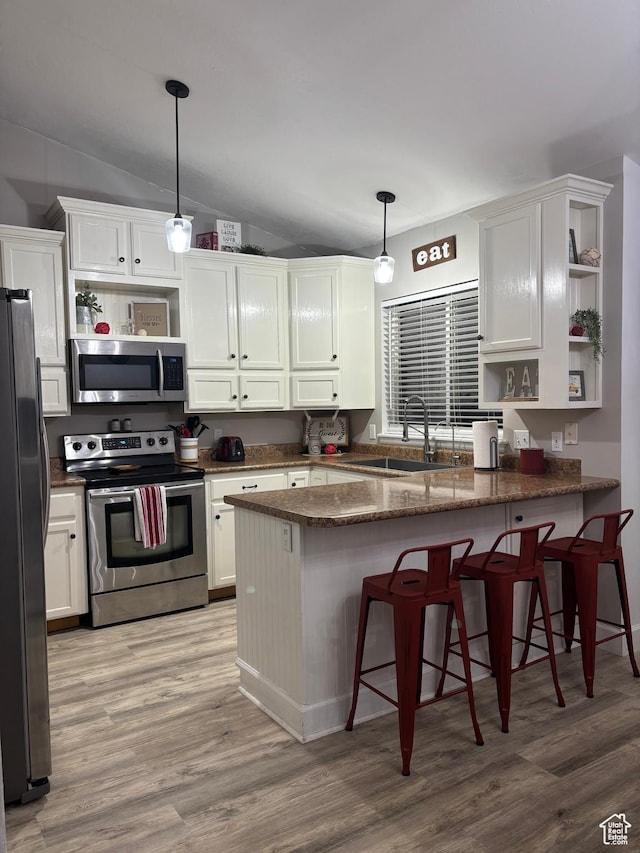 kitchen featuring open shelves, stainless steel appliances, white cabinets, a sink, and a peninsula