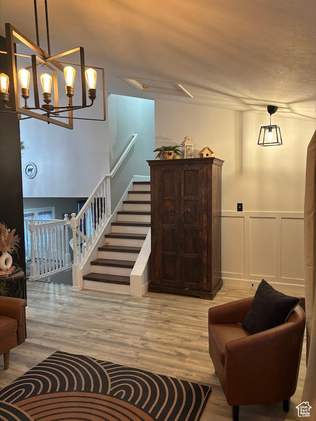 living room featuring stairs, wainscoting, wood finished floors, and a decorative wall
