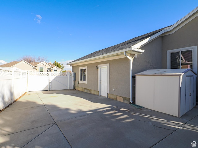121 E Amber Rd, Saratoga Springs, UT 84045 - rear view of house with a gate, stucco siding, a patio area, fence, and a storage unit
