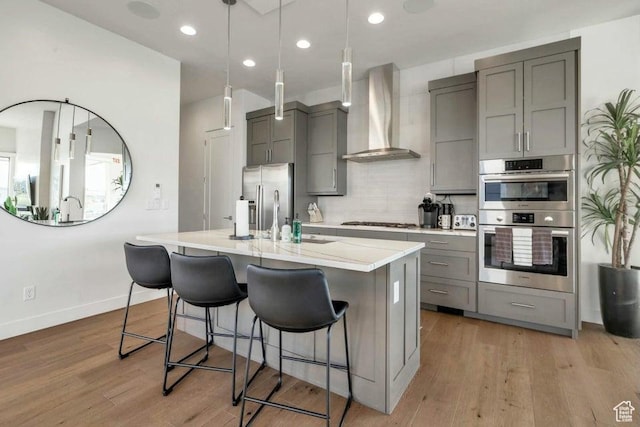 1478 W Torrey Rd, Hurricane, UT 84737 - kitchen featuring a kitchen island with sink, stainless steel appliances, wall chimney range hood, light wood-type flooring, and gray cabinets