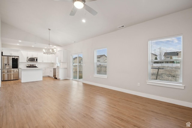3361 W Sophie Ln, West Haven, UT 84401 - unfurnished living room featuring ceiling fan with notable chandelier, light wood-style flooring, baseboards, and lofted ceiling