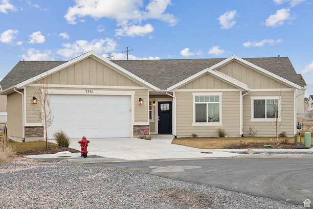 view of front of home featuring board and batten siding, roof with shingles, driveway, stone siding, and an attached garage