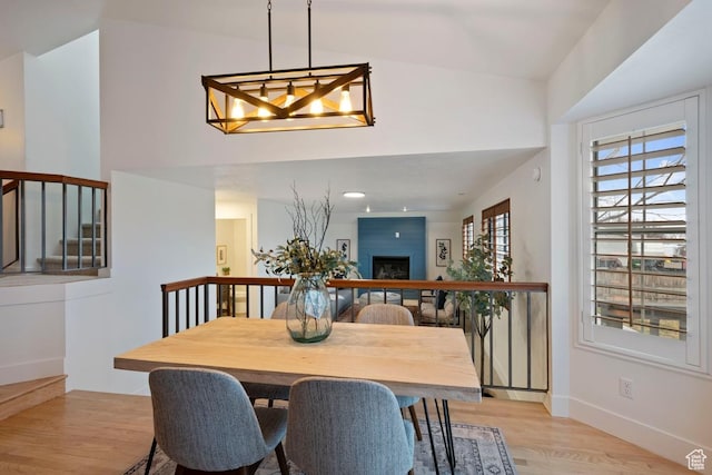 9971 S Dunsinane Dr W, South Jordan, UT 84009 - dining space featuring an inviting chandelier, a fireplace, light wood-style flooring, and baseboards