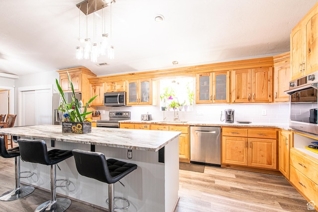 1027 S 920 W, Hurricane, UT 84737 - kitchen featuring decorative backsplash, appliances with stainless steel finishes, a kitchen breakfast bar, light wood-type flooring, and a sink