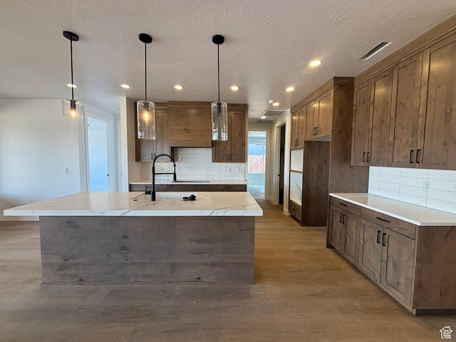 579 S 1800 W, Hurricane, UT 84737 - kitchen featuring hanging light fixtures, decorative backsplash, an island with sink, light stone countertops, and recessed lighting