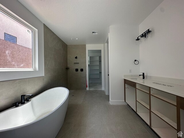 591 S 1800 W, Hurricane, UT 84737 - full bath featuring a textured ceiling, tile walls, a freestanding tub, vanity, and a walk in closet