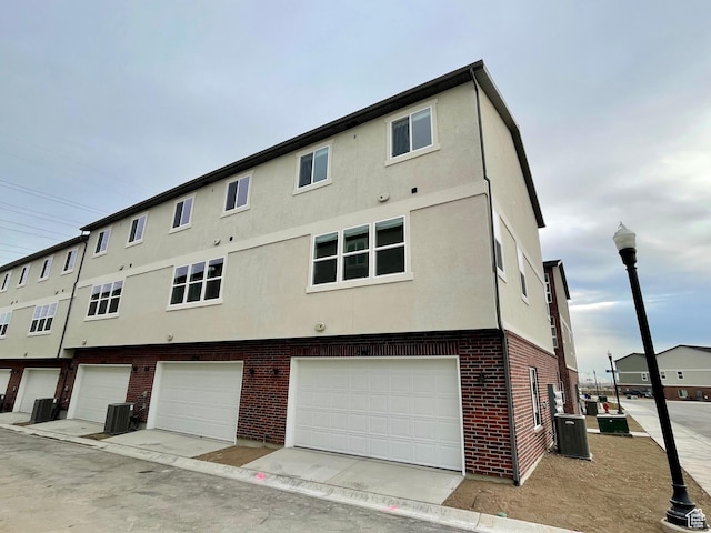 12941 S Corona Arch Ct Unit 571, Riverton, UT 84096 - rear view of house with brick siding, cooling unit, an attached garage, and stucco siding